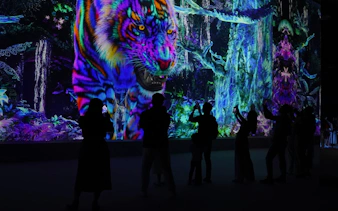 Digital art display of a vibrant tiger in Kuala Lumpur exhibition, visitors capturing the scene.