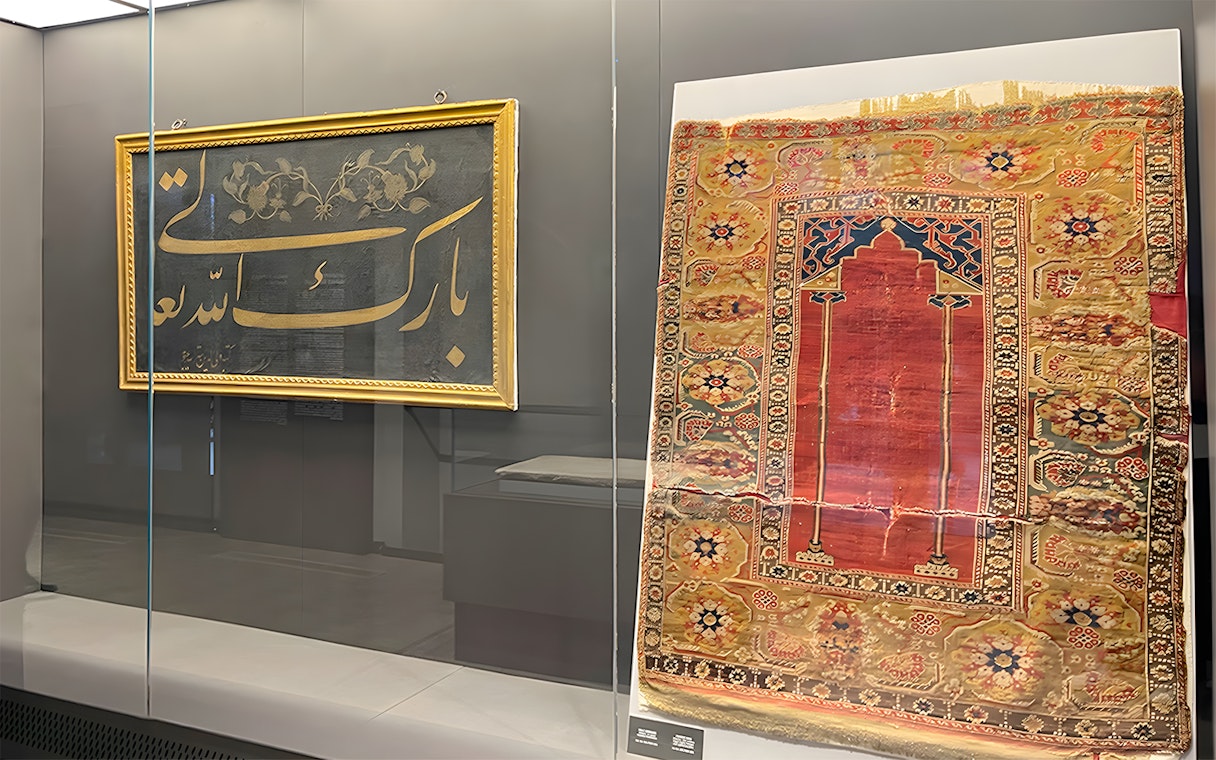 Framed calligraphy and ornate rug display at Hagia Sophia Museum.