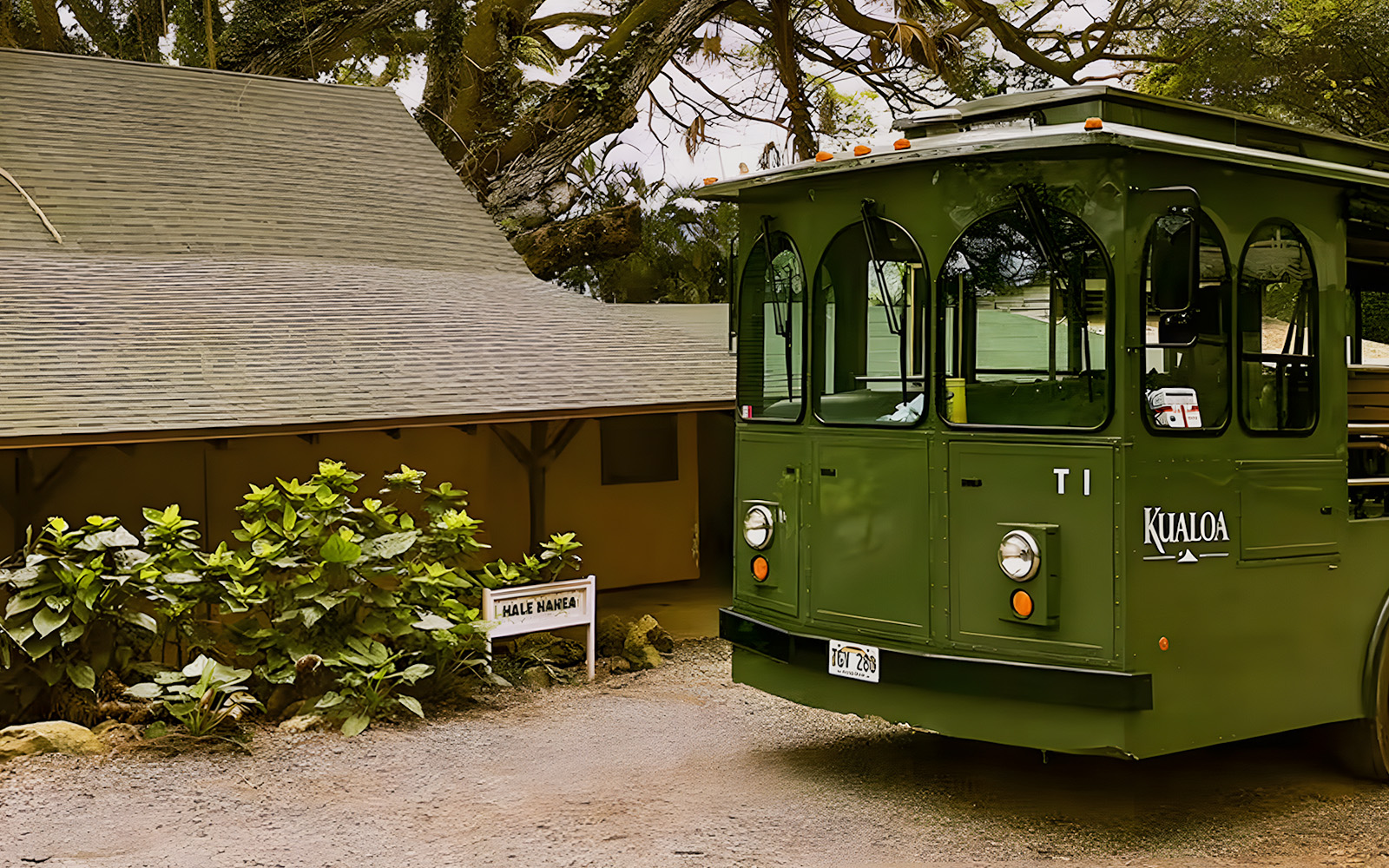 Kualoa Grown Tour trolley near Hale Nanea building surrounded by lush greenery.