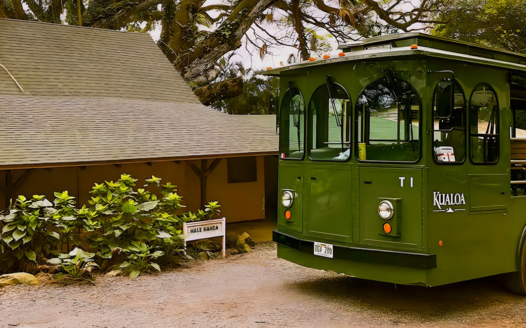 Kualoa Grown Tour trolley near Hale Nanea building surrounded by lush greenery.