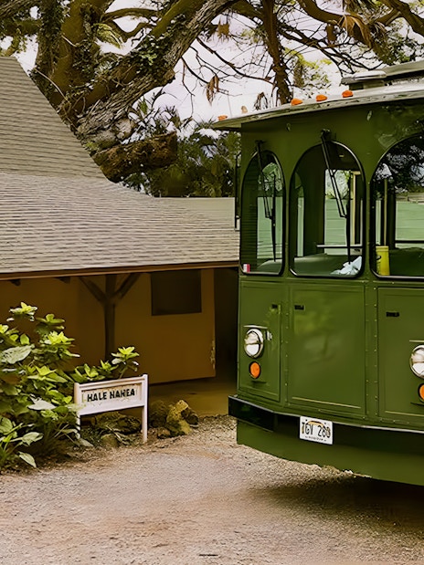 Kualoa Grown Tour trolley near Hale Nanea building surrounded by lush greenery.