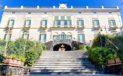 Elegant historic building with green shutters and stone steps in Naples, Italy.
