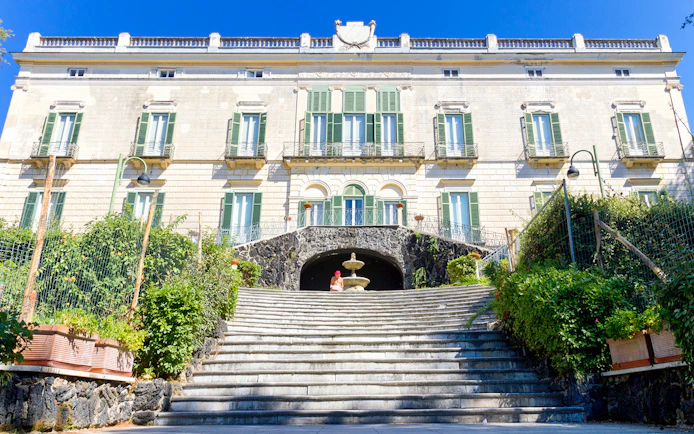 Elegant historic building with green shutters and stone steps in Naples, Italy.