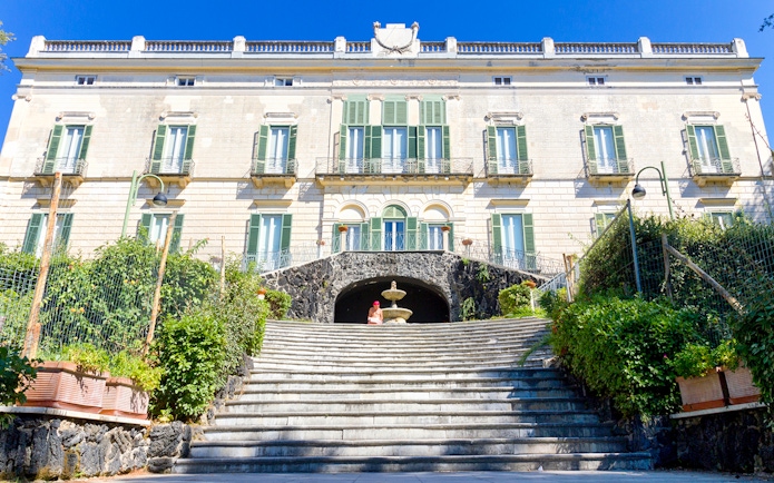 Elegant historic building with green shutters and stone steps in Naples, Italy.