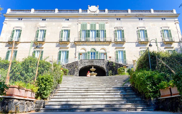 Elegant historic building with green shutters and stone steps in Naples, Italy.