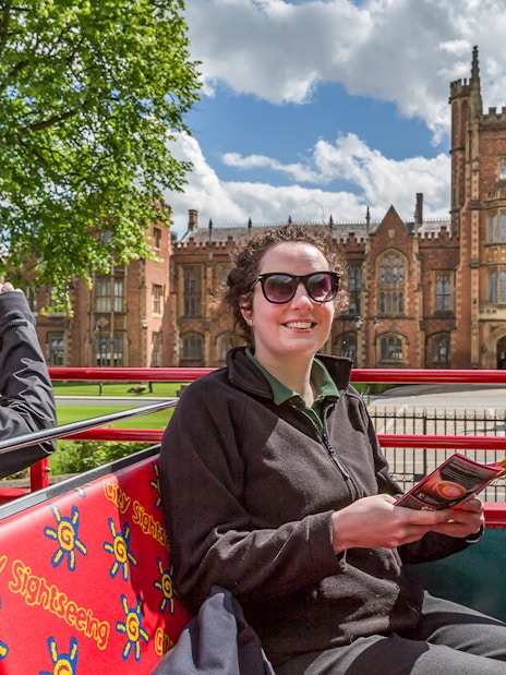 HOHO tour bus at Queen's University, Belfast with passengers enjoying the view.