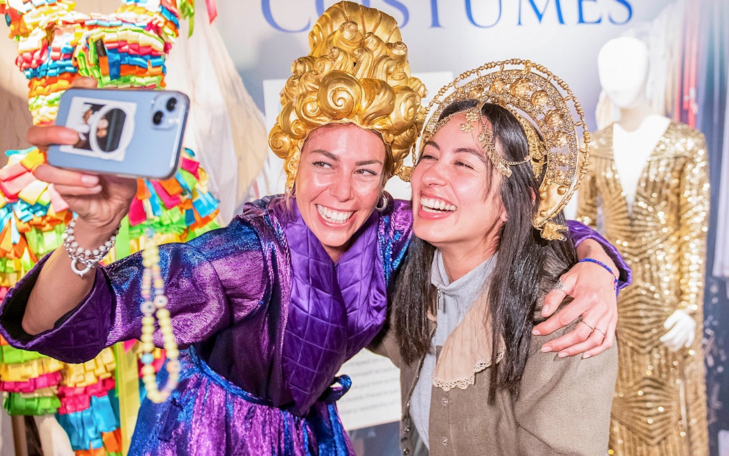 Visitors in colorful costumes taking a selfie at a museum exhibit during Globe Story and Guided Tours.