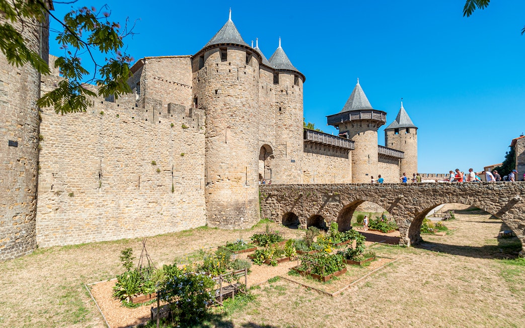 Ramparts of the medieval city of Carcassonne, France, with tourists on the stone bridge.