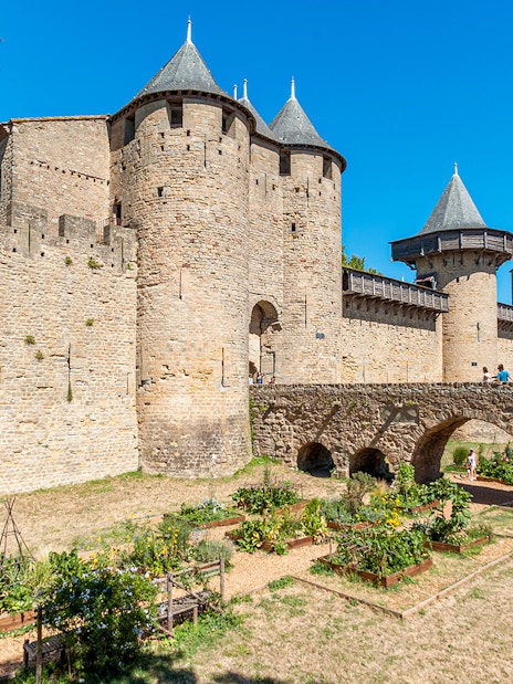 Ramparts of the medieval city of Carcassonne, France, with tourists on the stone bridge.