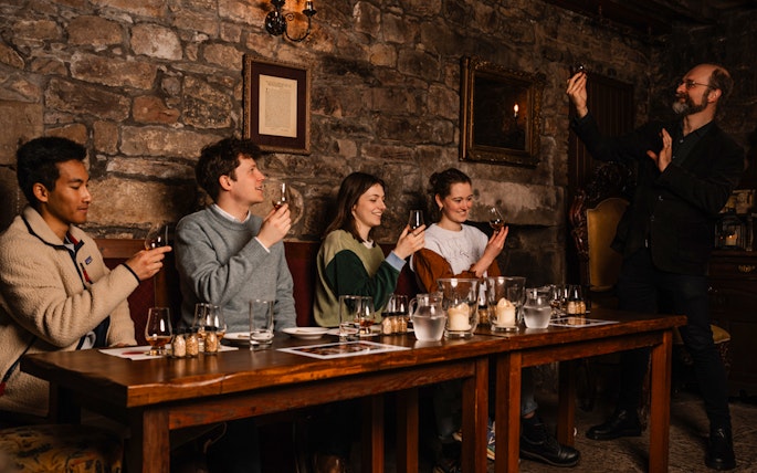 Guests enjoying whisky tasting at an underground tour in Edinburgh.