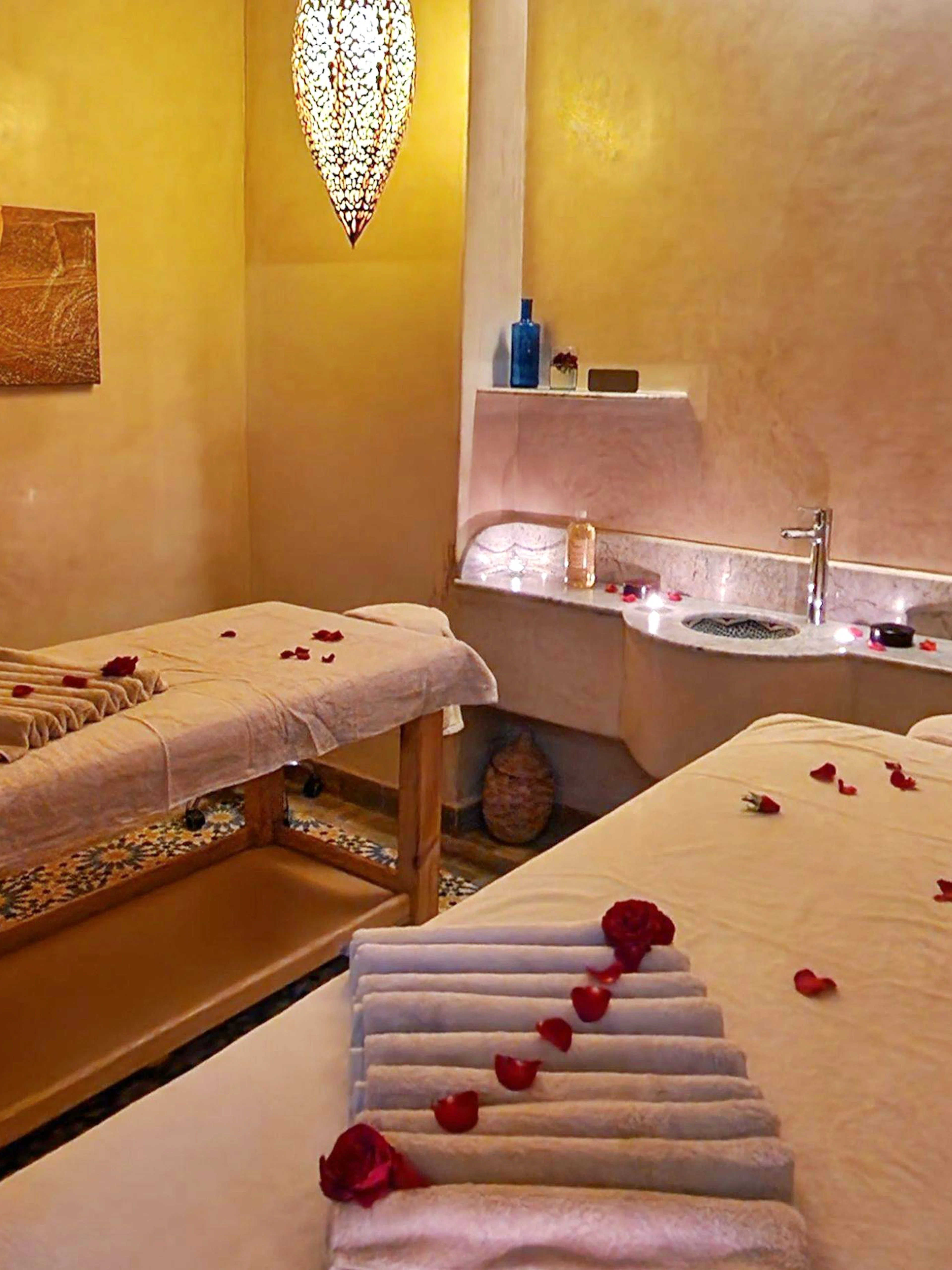 Massage room with two tables and rose petals at Le Bain Bleu Hammam & Spa, Marrakesh.