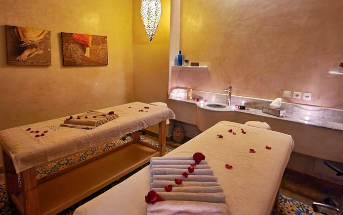 Massage room with two tables and rose petals at Le Bain Bleu Hammam & Spa, Marrakesh.