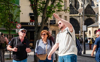 Tour guide explaining Notre-Dame's exterior to visitors on Île de la Cité, Paris.