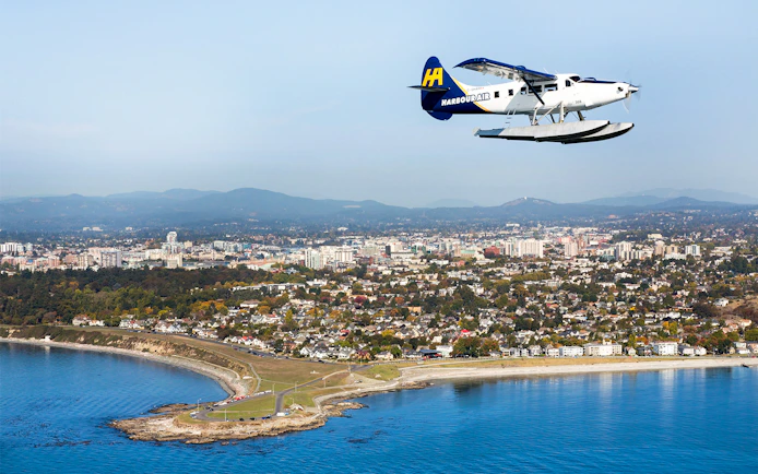 Seaplane flying over Victoria cityscape and coastline during scenic tour.