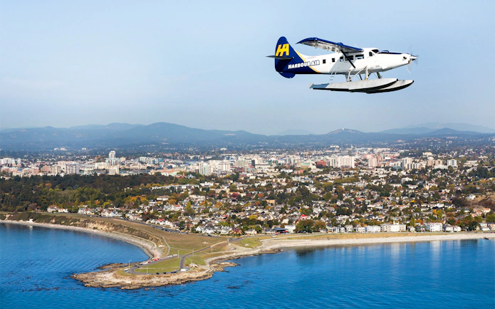 Seaplane flying over Victoria cityscape and coastline during scenic tour.
