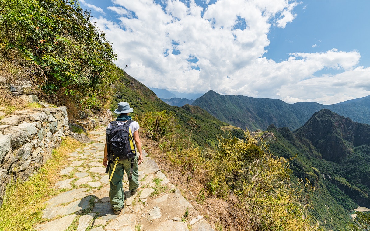 Hiker on a stone path overlooking Vilcanota Valley near Machu Picchu.