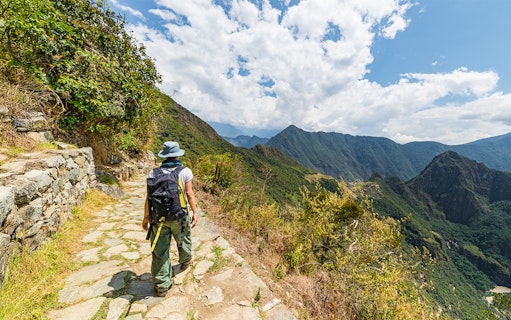 Hiker on a stone path overlooking Vilcanota Valley near Machu Picchu.