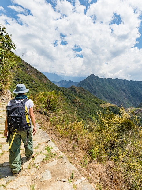 Hiker on a stone path overlooking Vilcanota Valley near Machu Picchu.