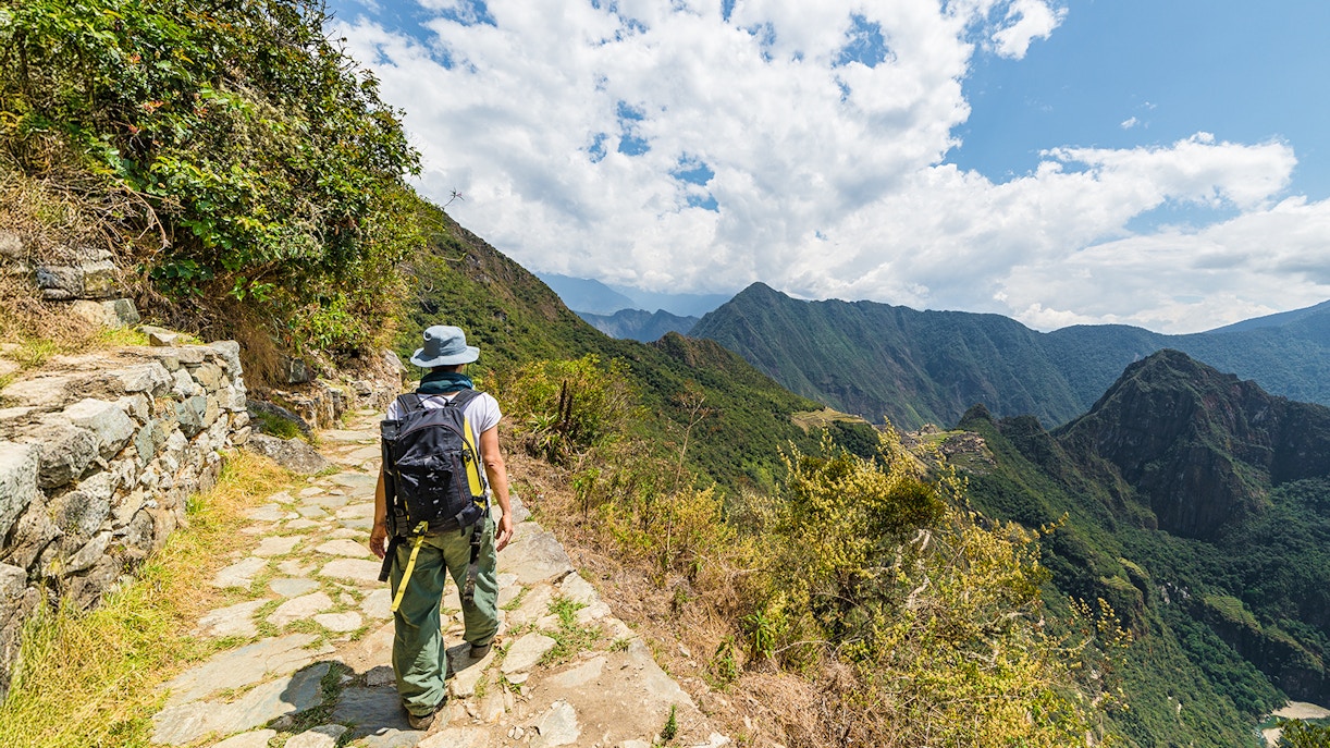 Hiker on a stone path overlooking Vilcanota Valley near Machu Picchu.