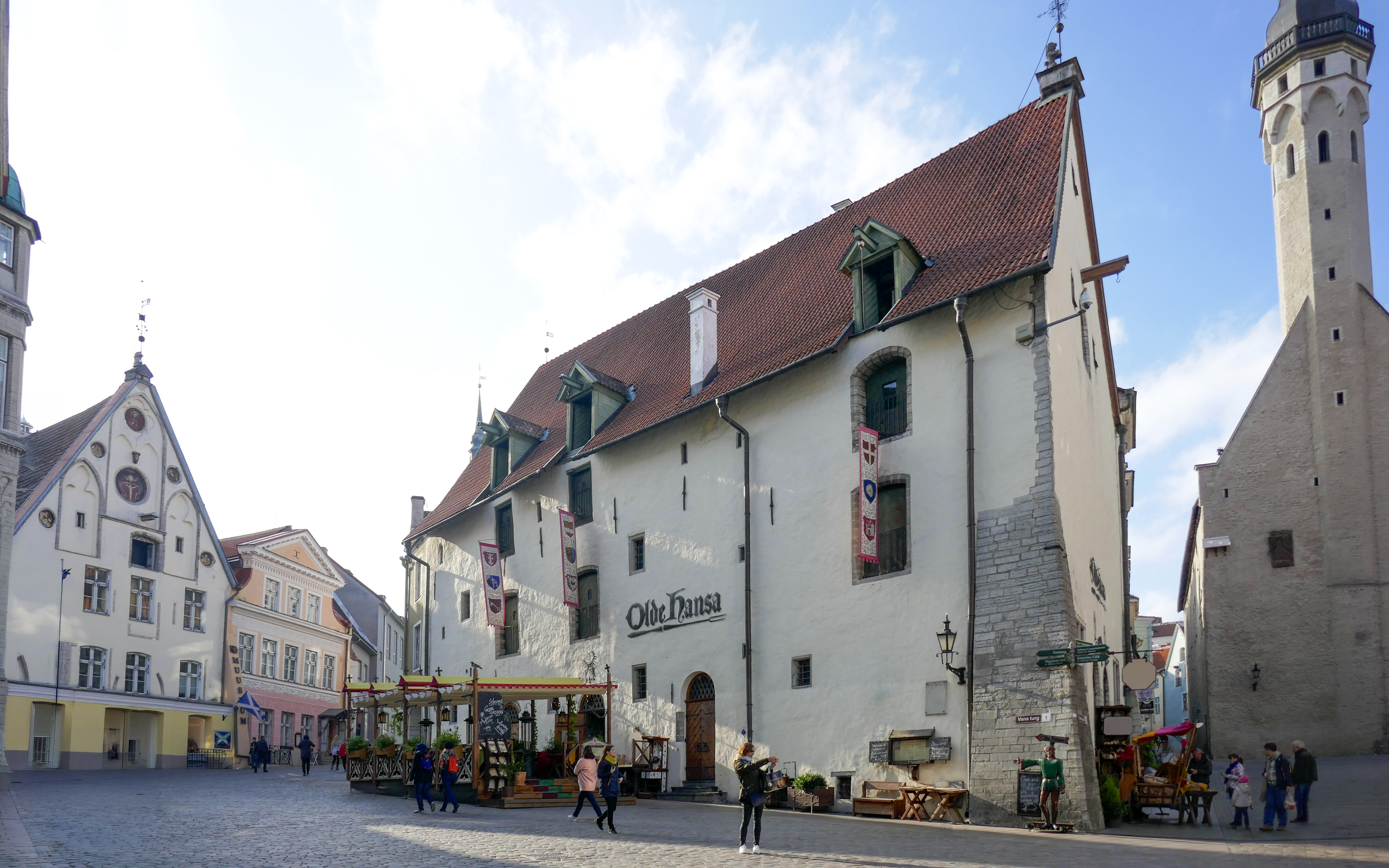 Olde Hansa pub in Tallinn's historic square with people walking nearby.