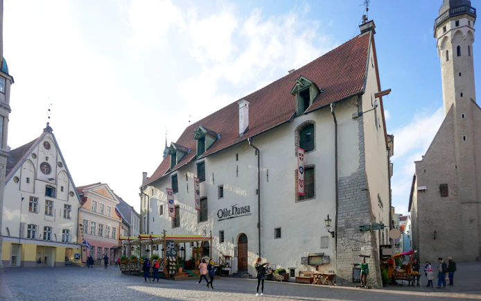 Olde Hansa pub in Tallinn's historic square with people walking nearby.