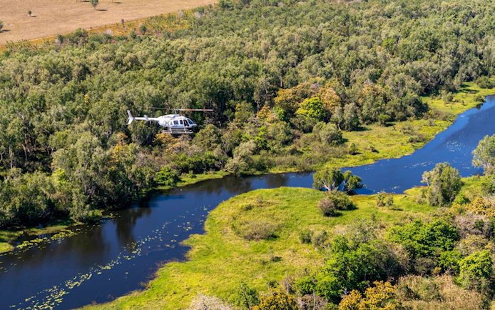 Helicopter flying over Finniss River landscape on Top End Safari Camp tour from Darwin.
