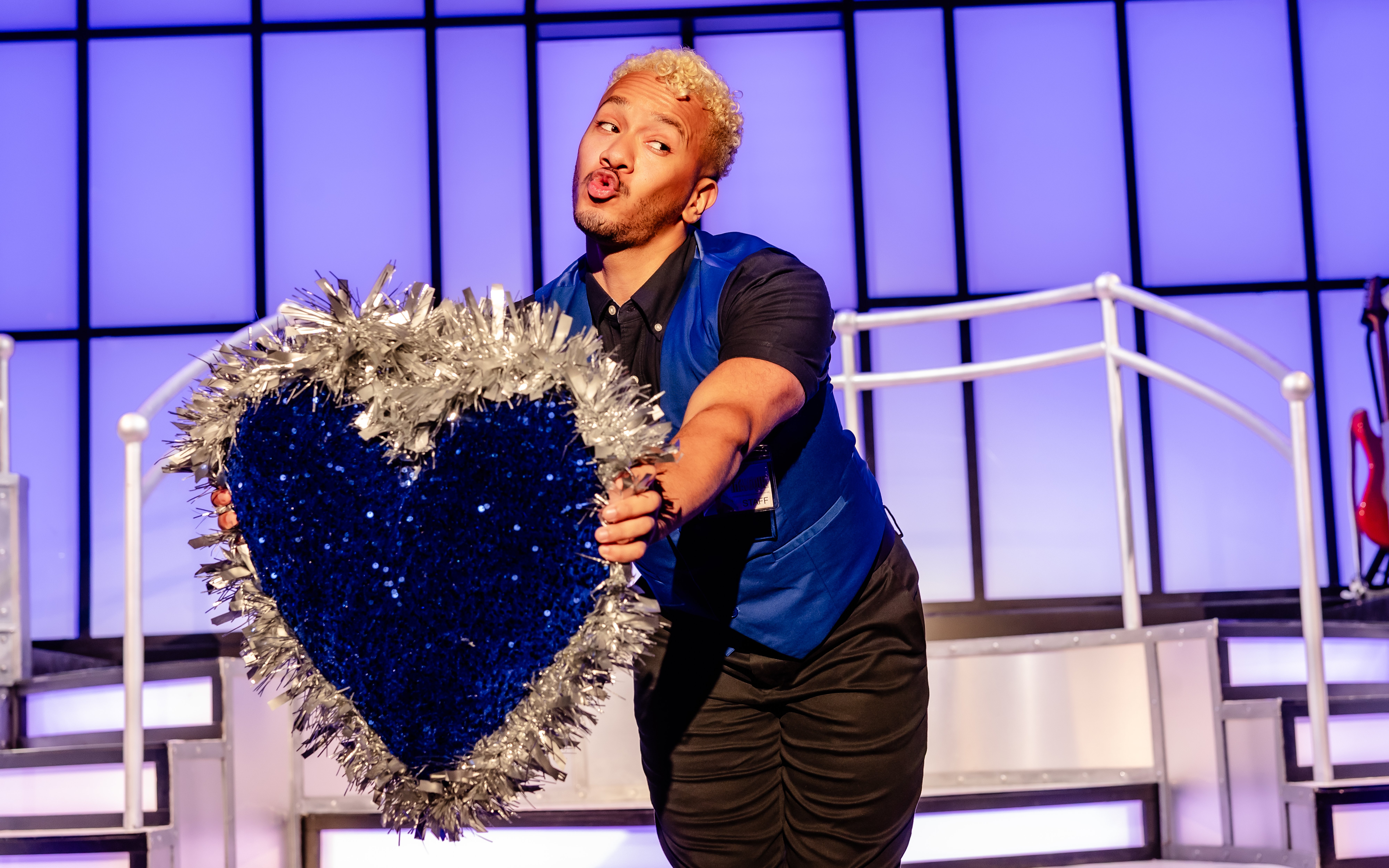 Performer holding a glittery heart prop on stage during Titanique Westend show.