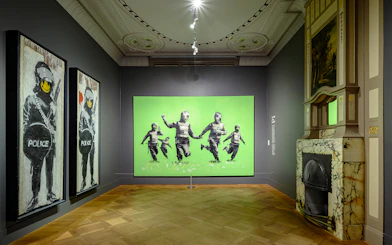 Banksy artworks displayed at Moco Museum, Amsterdam, featuring police figures with smiley faces.