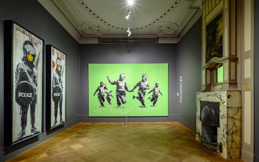 Banksy artworks displayed at Moco Museum, Amsterdam, featuring police figures with smiley faces.