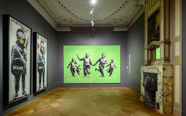 Banksy artworks displayed at Moco Museum, Amsterdam, featuring police figures with smiley faces.