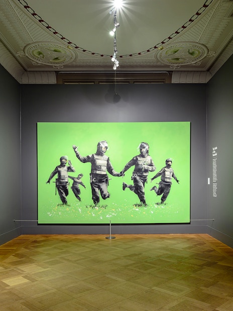 Banksy artworks displayed at Moco Museum, Amsterdam, featuring police figures with smiley faces.