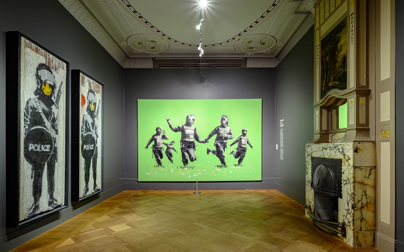 Banksy artworks displayed at Moco Museum, Amsterdam, featuring police figures with smiley faces.