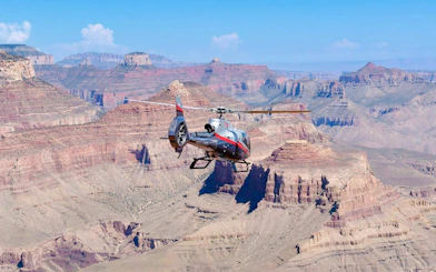 Helicopter flying over Grand Canyon South Rim with scenic views.