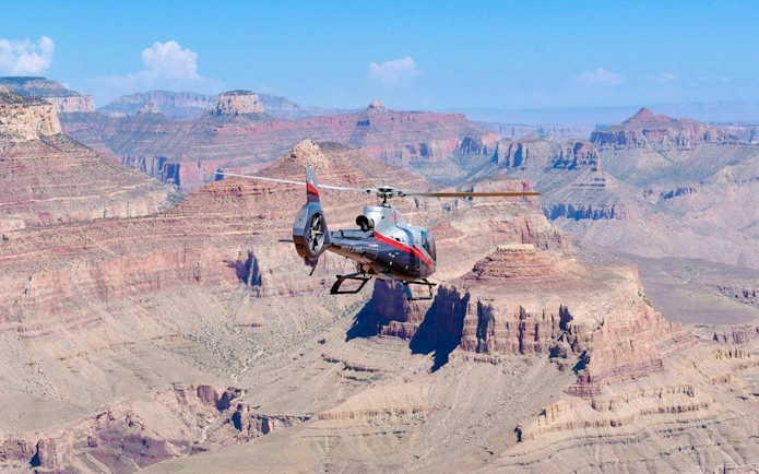 Helicopter flying over Grand Canyon South Rim with scenic views.