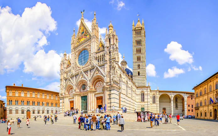 Siena Cathedral facade with tourists in Piazza del Duomo, Siena, Italy.