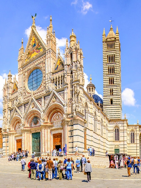 Siena Cathedral facade with tourists in Piazza del Duomo, Siena, Italy.