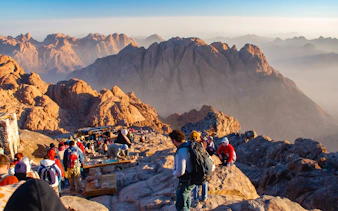 Group of tourists hiking on Mount Sinai with rocky peaks in the background.