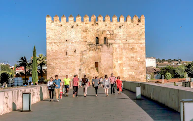 Visitors walking towards the historic gate of the Cordoba Mosque-Cathedral on a sunny day.