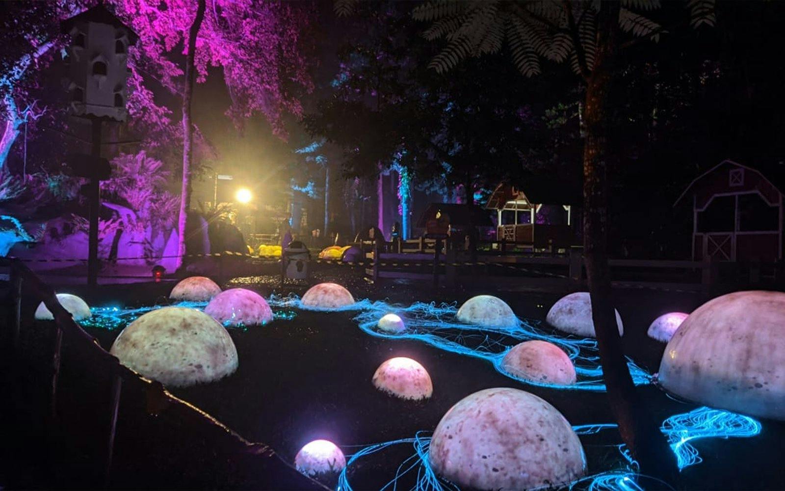 Glowing domes and neon lights at Dairyland Riverside Puncak night attraction.