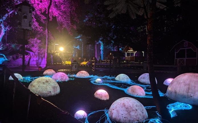 Glowing domes and neon lights at Dairyland Riverside Puncak night attraction.
