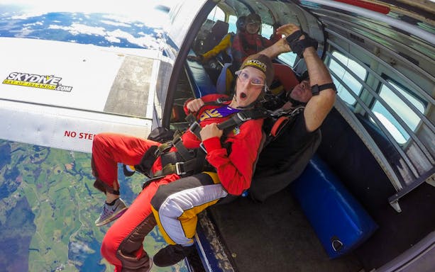 Tandem skydivers preparing to jump from plane over Bay of Islands at 12,000 ft.