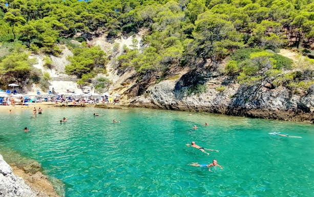 Swimmers enjoying clear waters near rocky coastline, Tremiti Islands, Italy.
