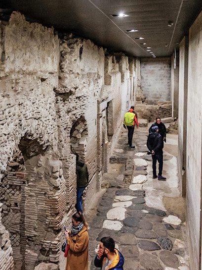 Visitors exploring ancient stone passageways in Naples Underground Tours.