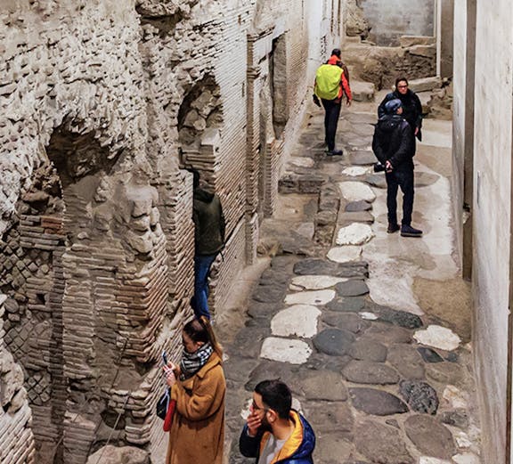 Visitors exploring ancient stone passageways in Naples Underground Tours.