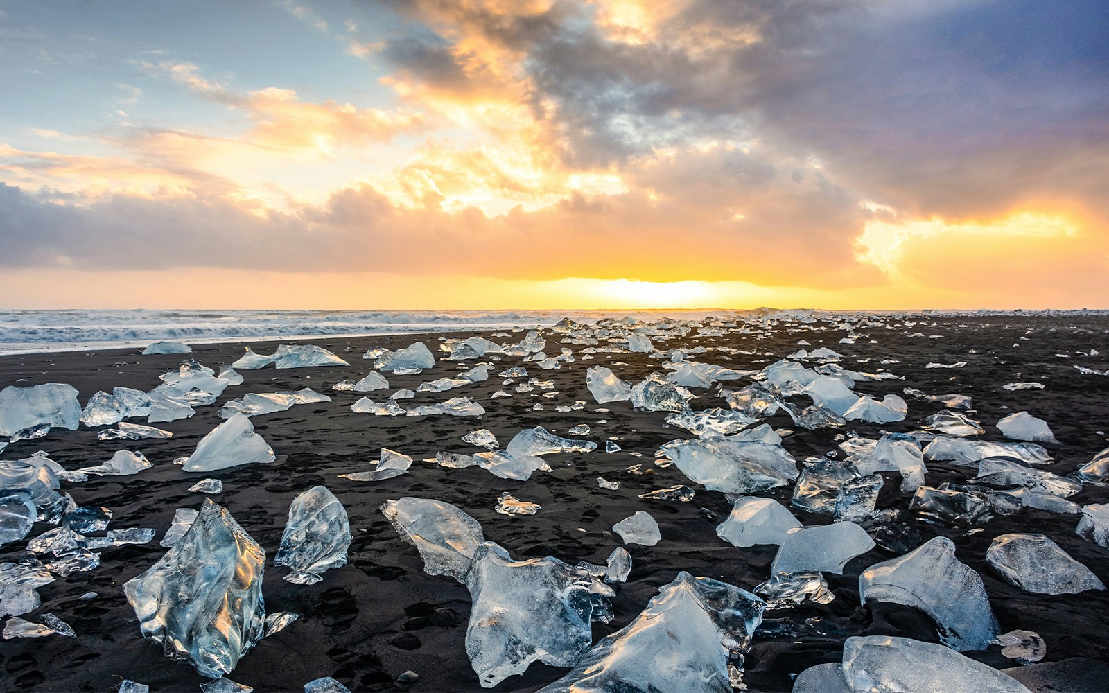 Sunset over Diamond Beach with icebergs on volcanic black sand, Jokulsarlon glacier lagoon, Iceland.