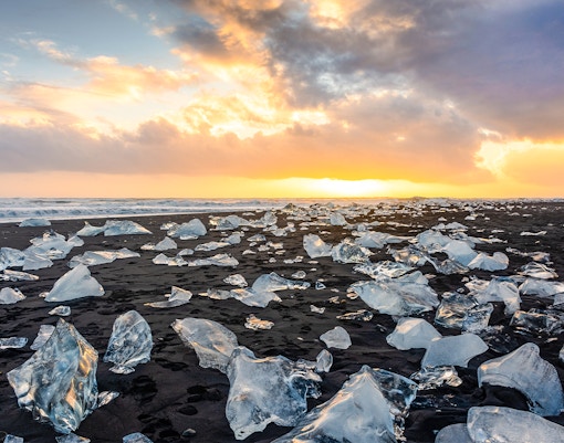 Sunset over Diamond Beach with icebergs on volcanic black sand, Jokulsarlon glacier lagoon, Iceland.
