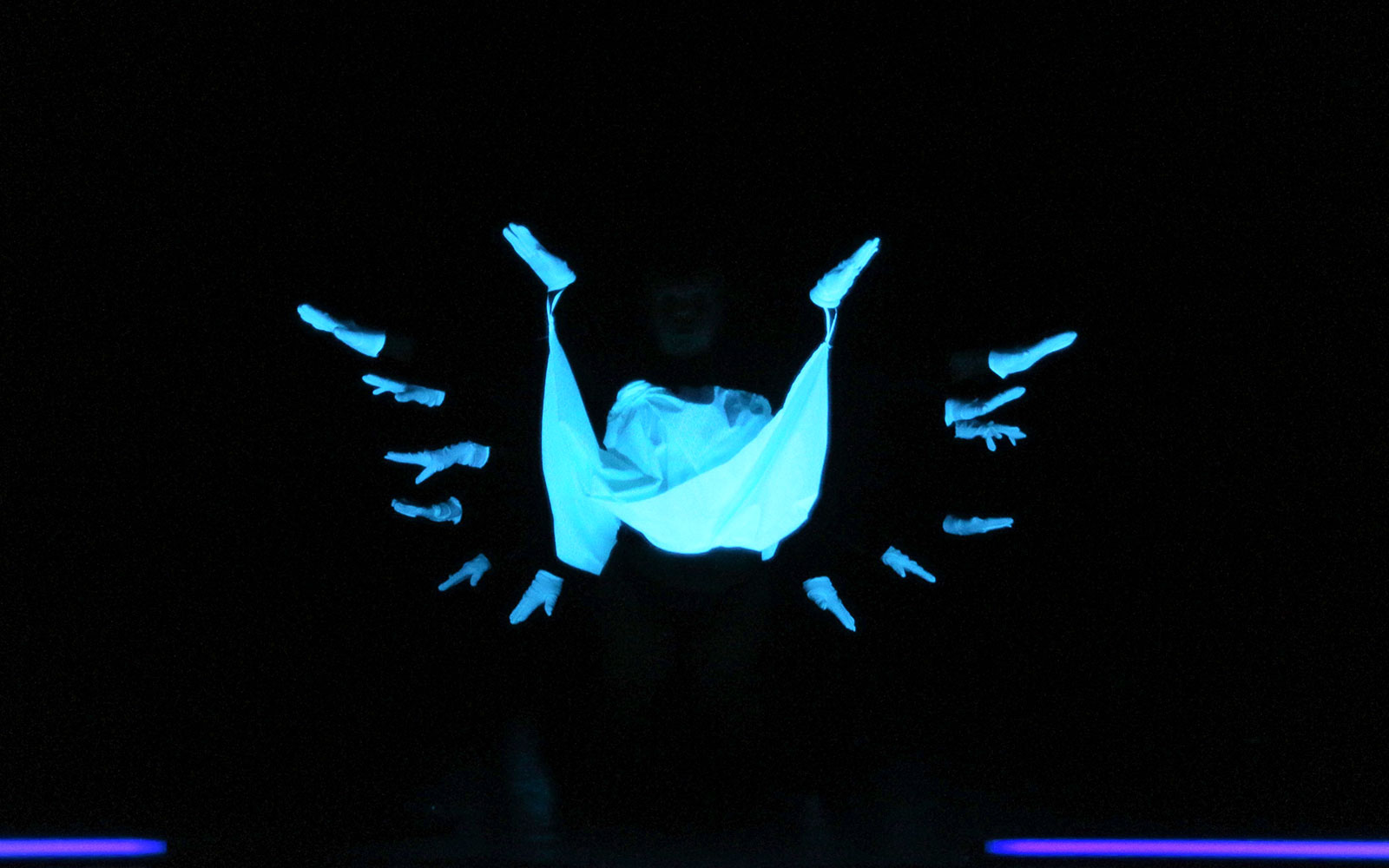 Performers in black light theatre, Prague, with glowing hands and fabric.