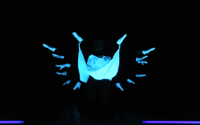 Performers in black light theatre, Prague, with glowing hands and fabric.