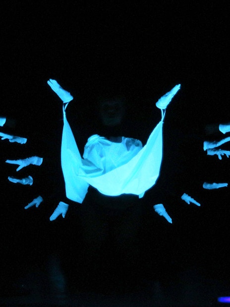 Performers in black light theatre, Prague, with glowing hands and fabric.