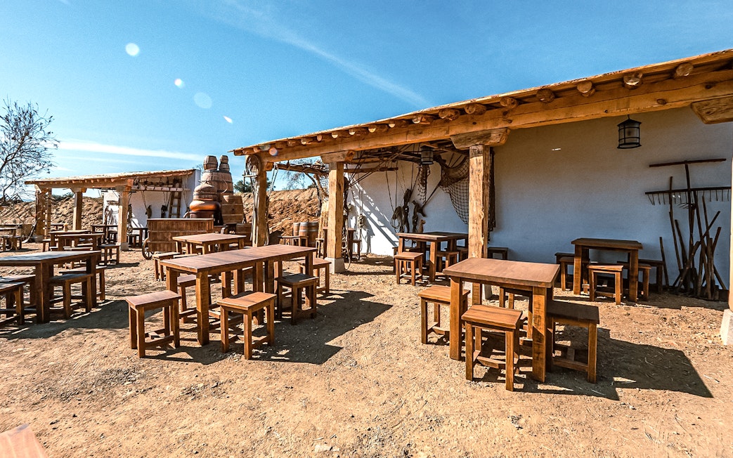 Outdoor seating area at Puy du Fou España park with rustic wooden tables and chairs.